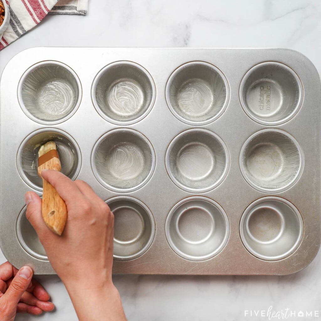 Spraying muffin pan with nonstick cooking spray.