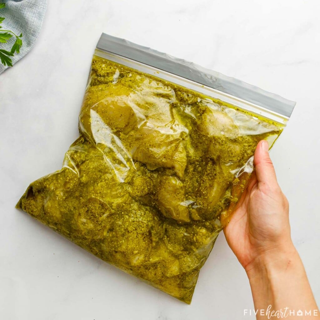 Plastic baggie of chicken breasts marinated in pesto.