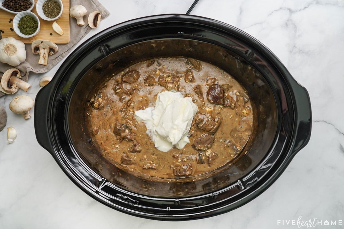 Stirring sour cream into Beef Stroganoff Crock Pot.