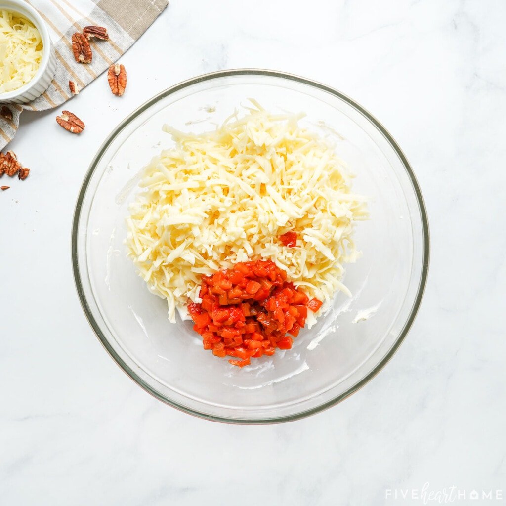 Adding grated cheddar and pimentos to make pimento cheese.