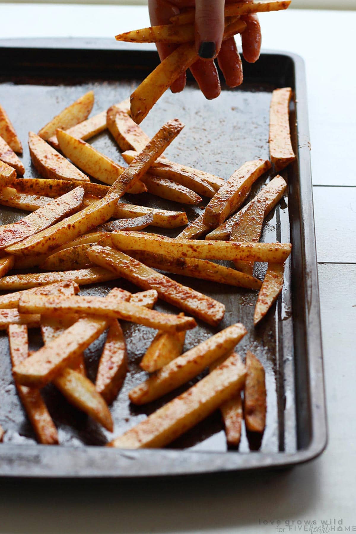 French fries seasoned on pan and ready for oven.