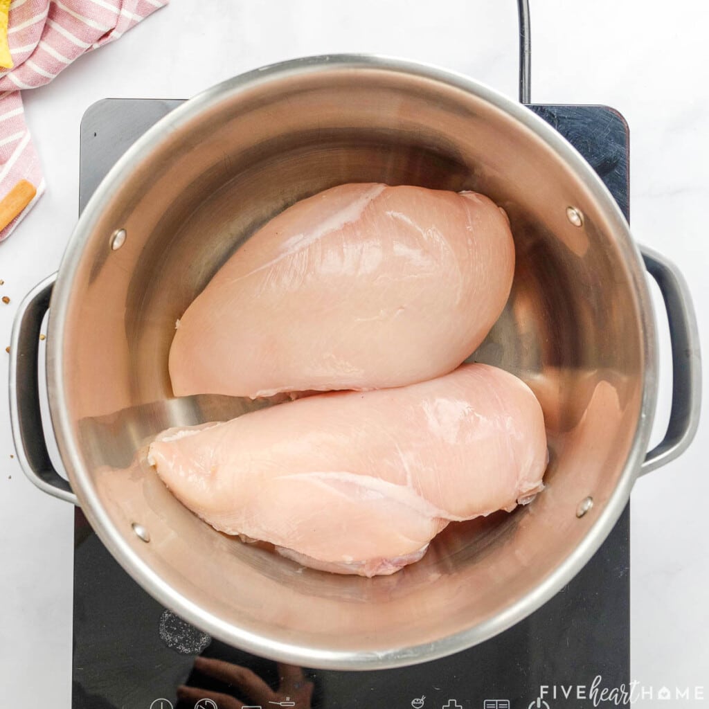 Chicken breasts in pot on stove.