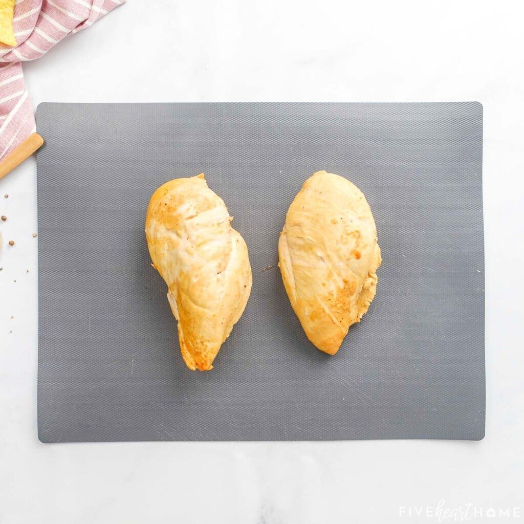 Cooked chicken breasts on cutting board.