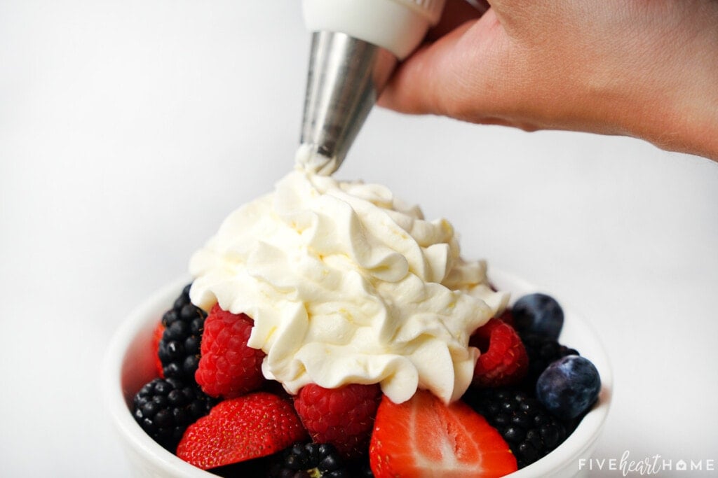Lemon Whipped Cream piped over bowl of berries.