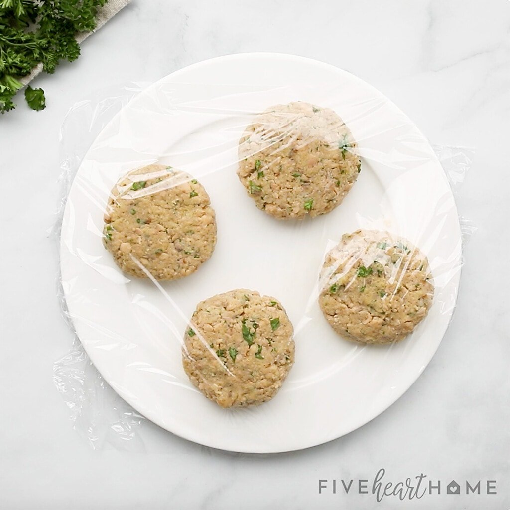 Salmon cakes on plate covered in plastic wrap.