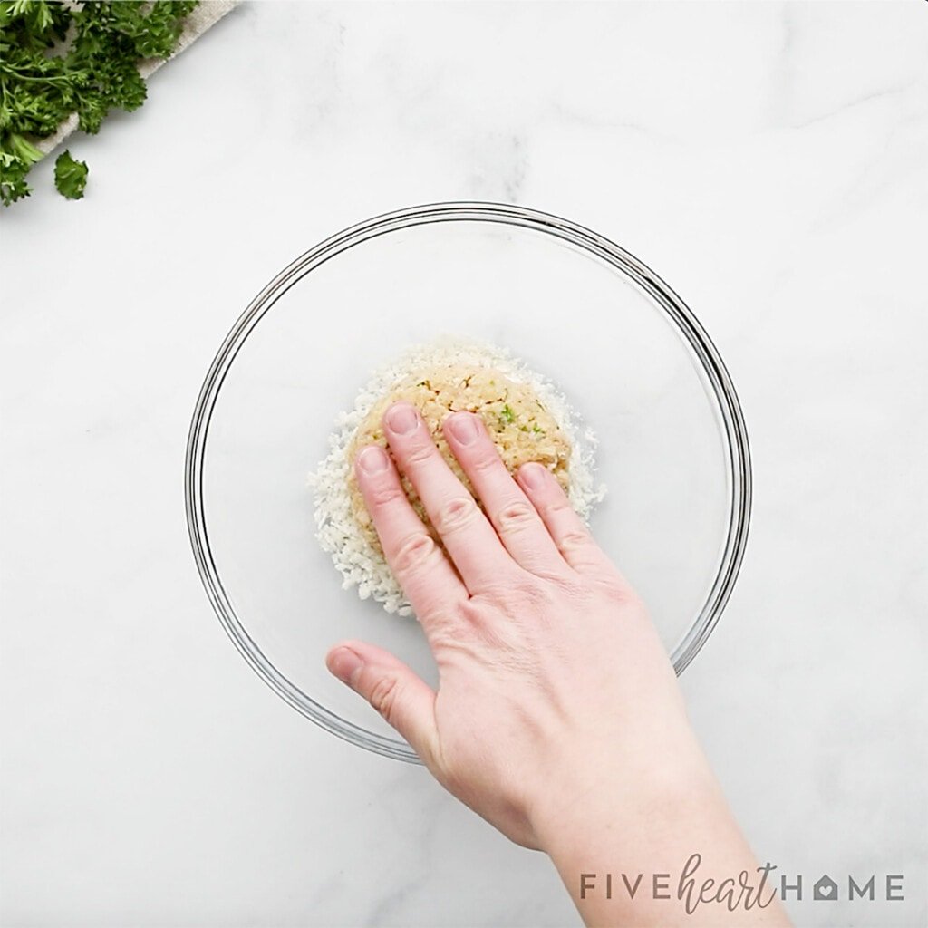 Pressing salmon croquette into parmesan coating.