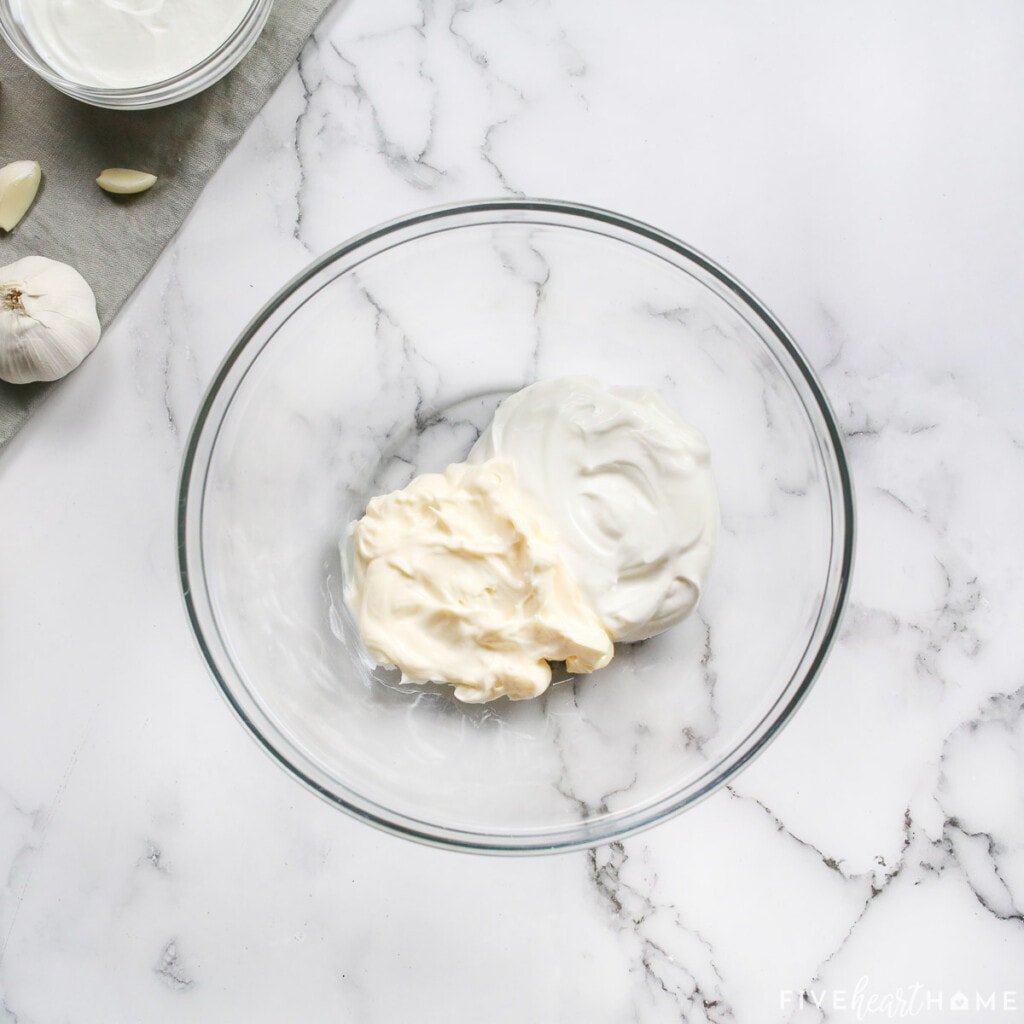 Mayonnaise and sour cream measured into a bowl to make parmesan crusted chicken with mayo.