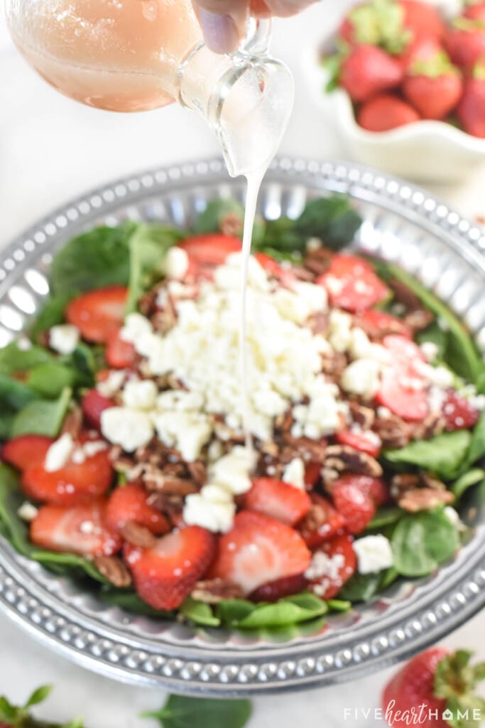 Strawberry spinach salad dressing poured onto salad.