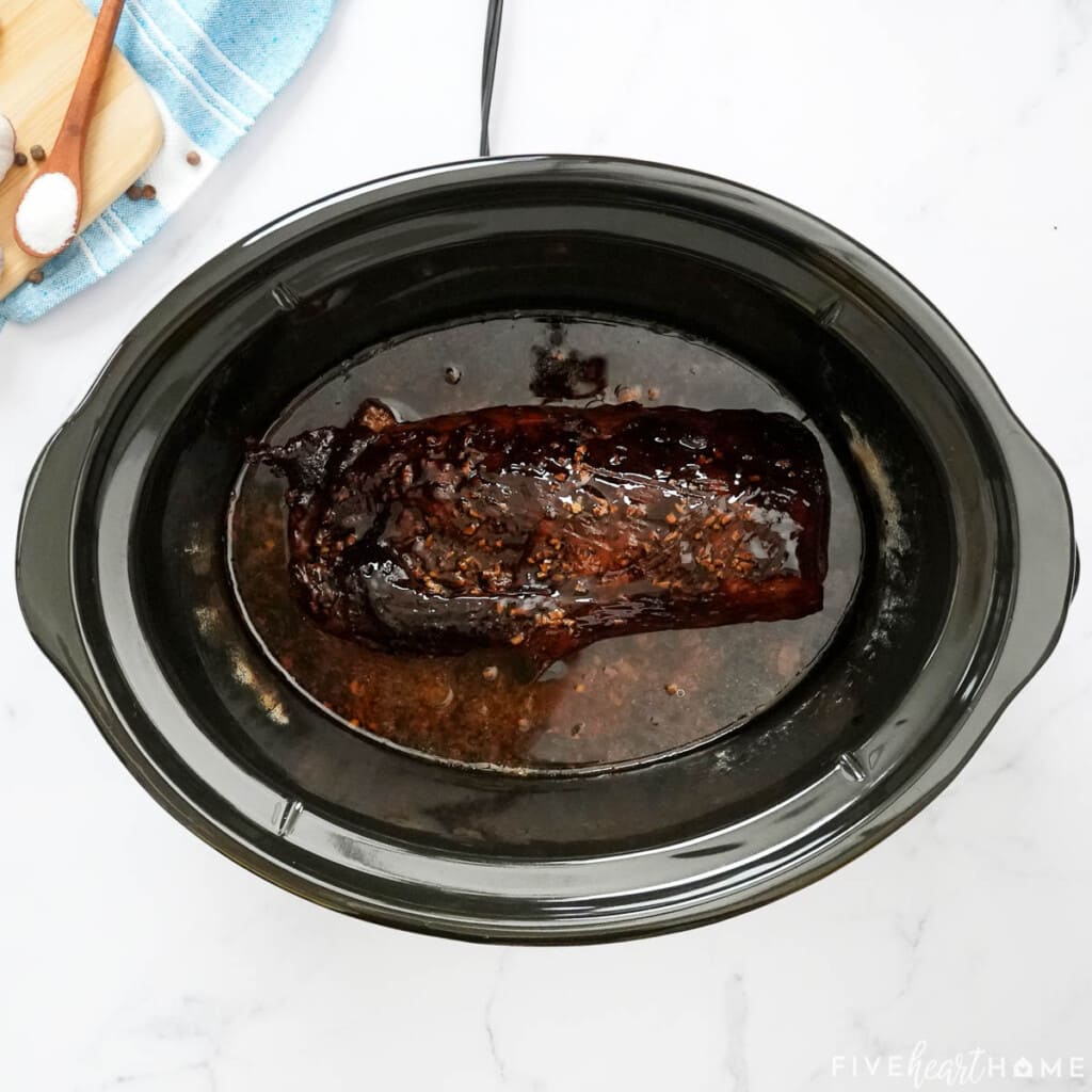 Glaze brushed on pork loin in crock pot.