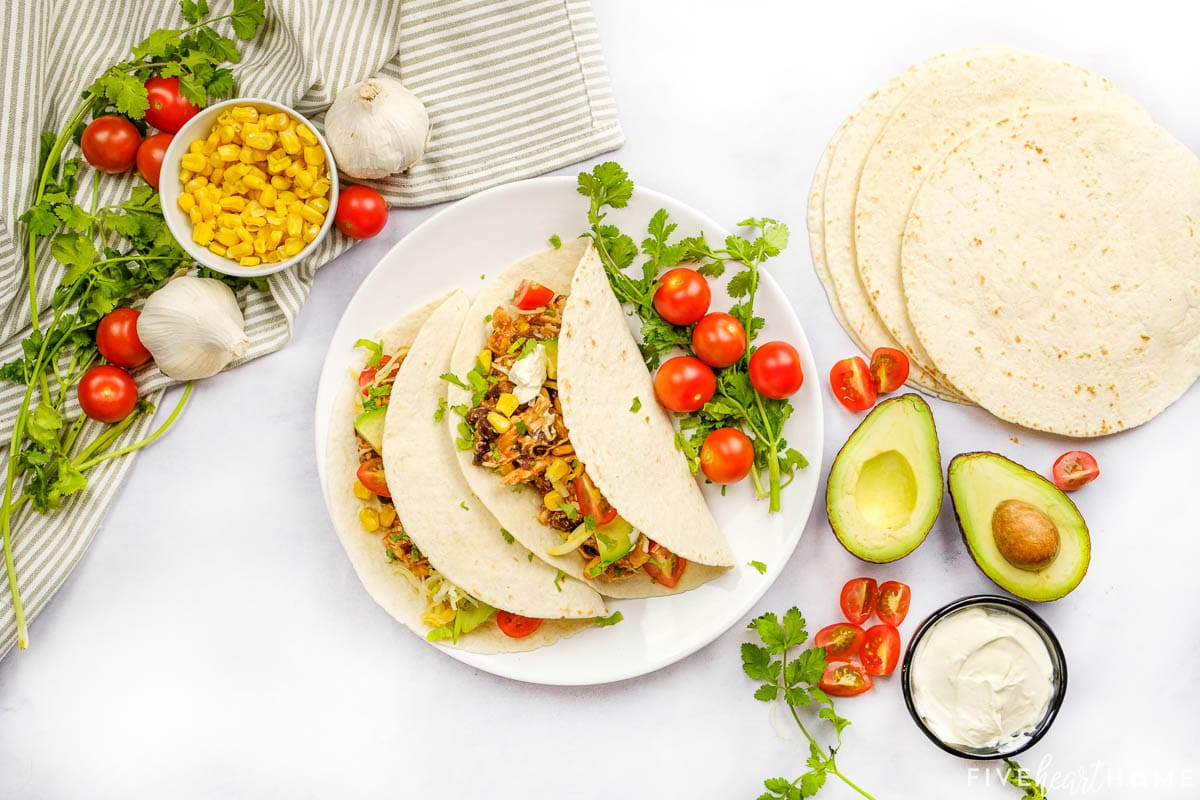 Aerial view of chicken tacos with ingredients on table.