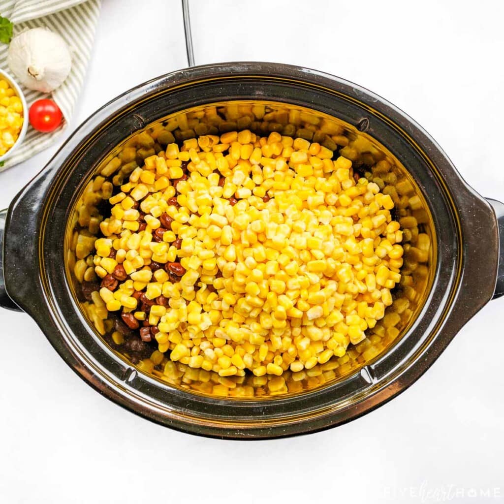 Adding black beans and corn to slow cooker.