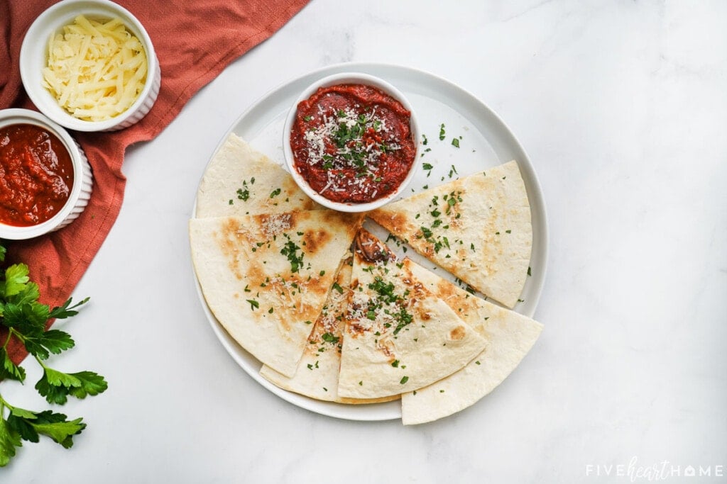 Aerial view of Pizza Quesadilla on plate with dipping sauce.