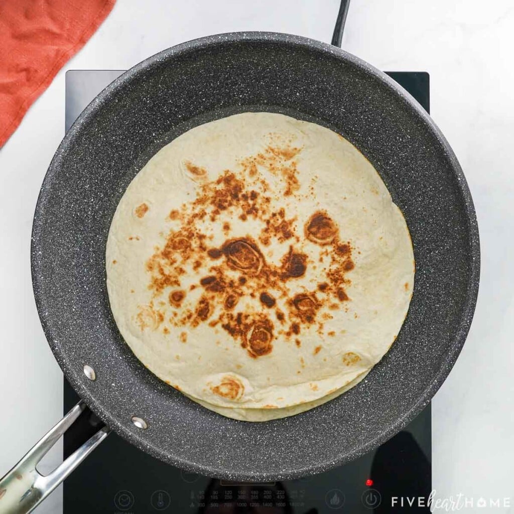 Pizza Quesadilla browned on one side in pan.