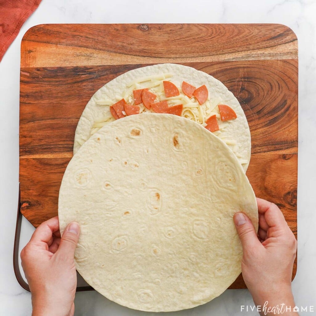 Placing top tortilla on Pizza Quesadilla.