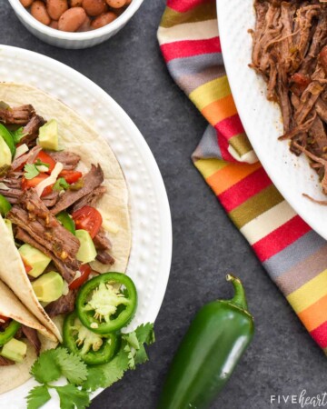 Shredded Beef on platter and plate of tacos.