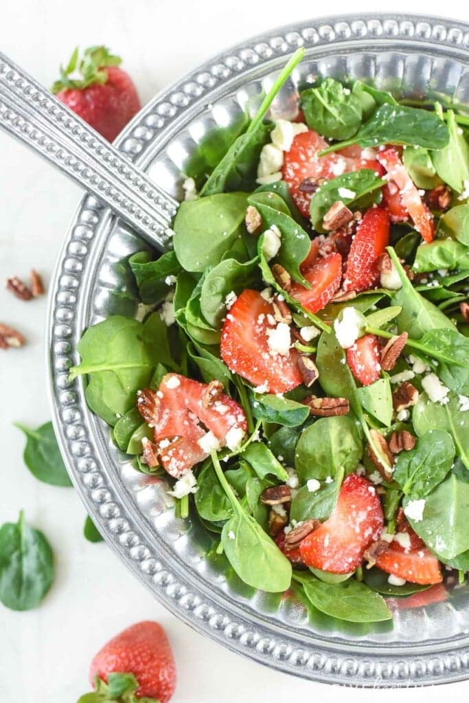 Spinach Salad with Strawberries tossed with pewter serving spoons.