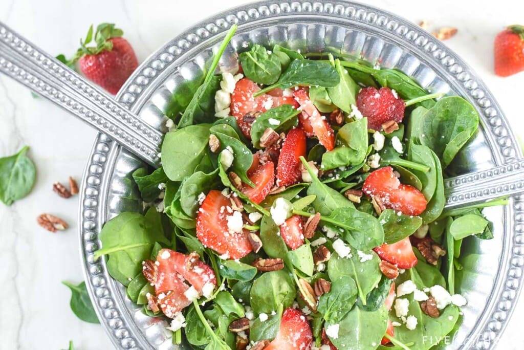 Aerial view of Spinach Salad with Strawberries with serving spoons.