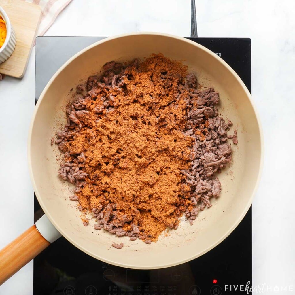 Adding taco seasoning to ground beef for Taco Hamburger Helper.