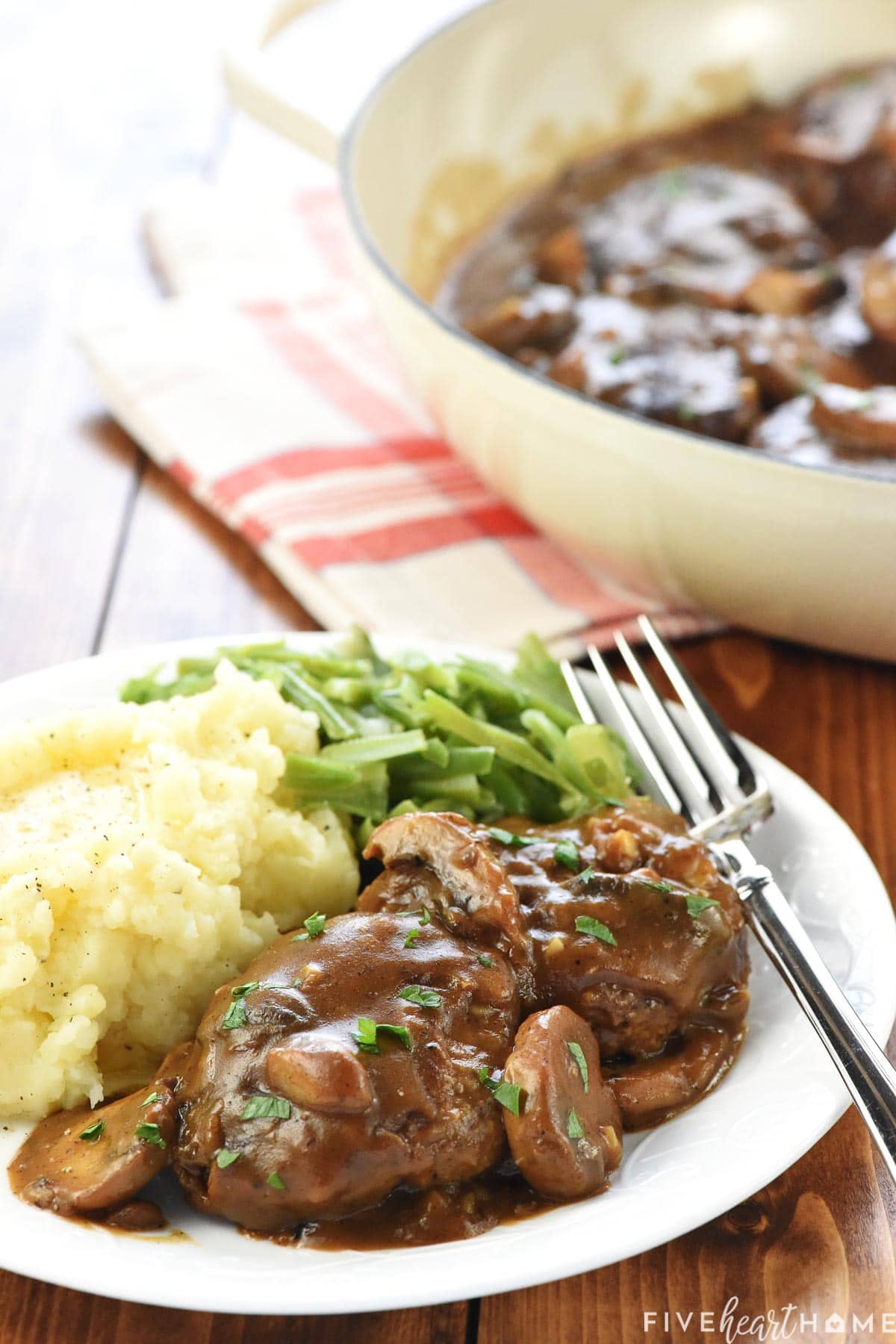 Hamburger Steak and gravy in skillet and on plate.