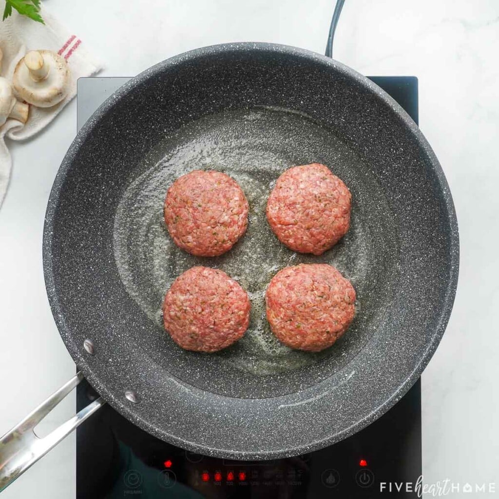 Browning hamburger steaks in a pan.