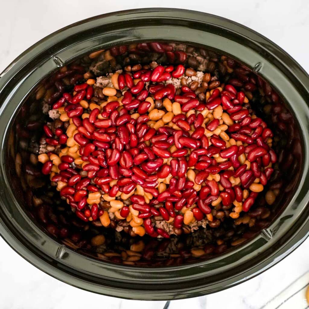 Adding beans to slow cooker for 3 Bean Chili recipe.