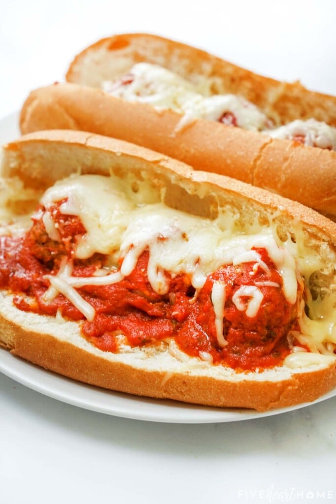Meatball sub recipe as two sandwiches on plate.