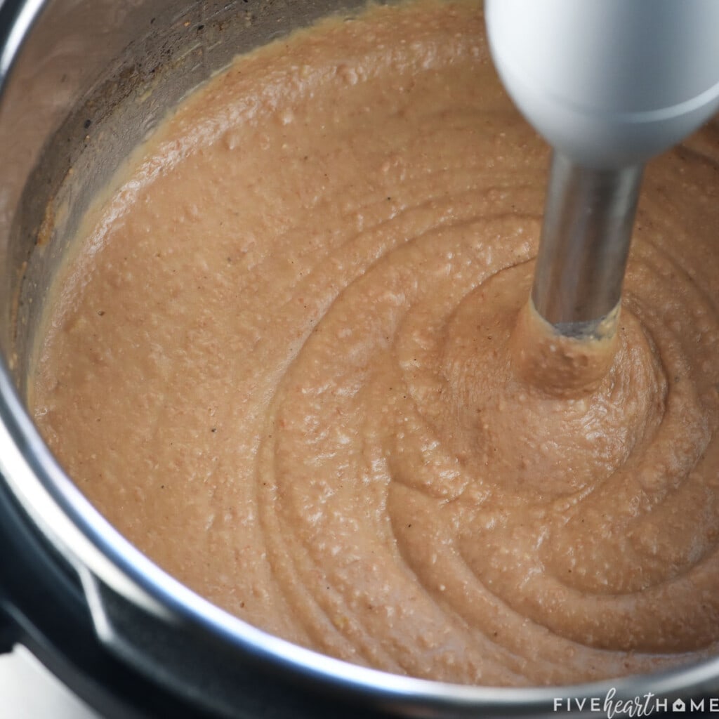 Homemade refried beans being pureed in pressure cooker.