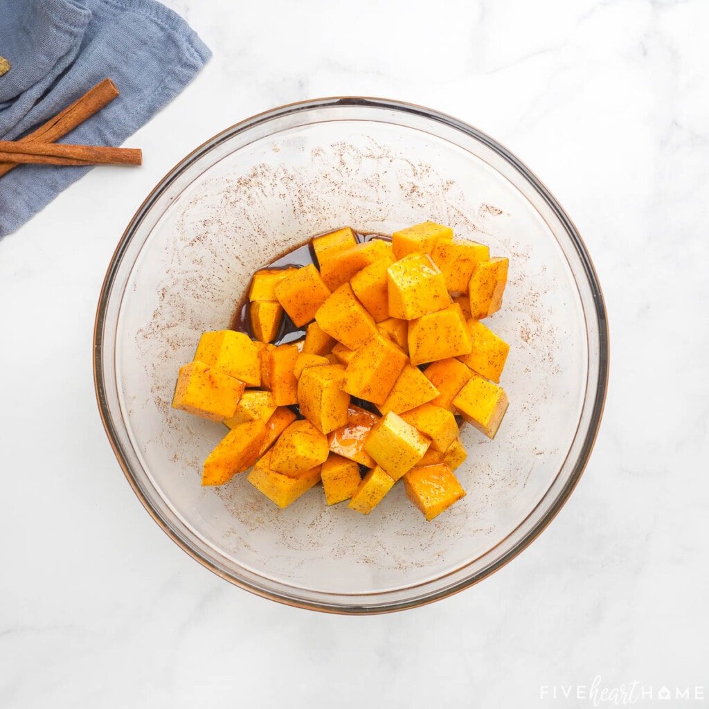 Glazing in a bowl for roast butternut squash cubes.