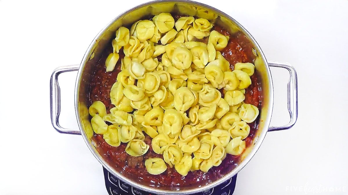 Adding marinara sauce and cheese tortellini to pot.