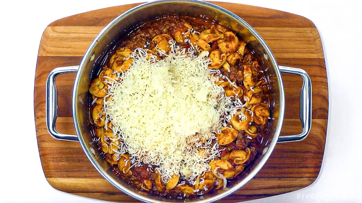 Adding cheese to make tortellini bake.