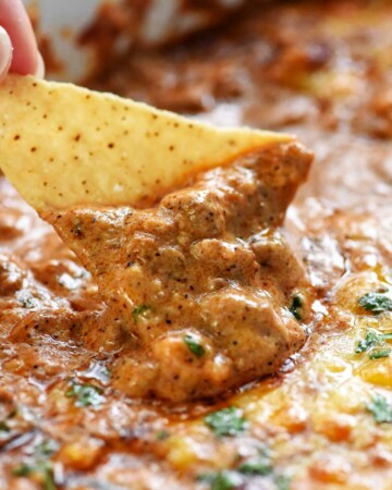Beef Enchilada Dip being scooped up by a tortilla chip.