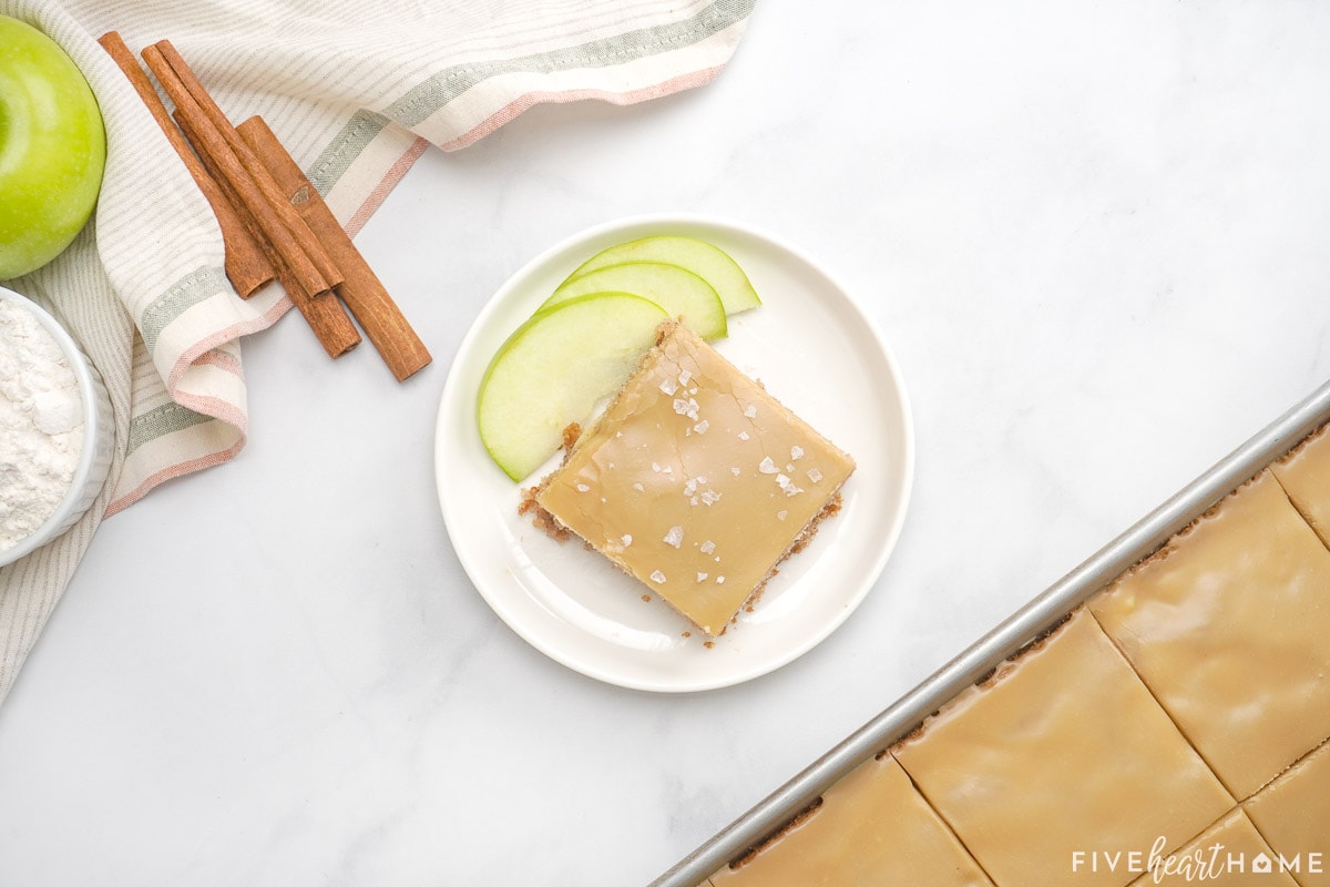 Slice of caramel apple sheet cake on plate with sliced caramel sheet cake in pan.