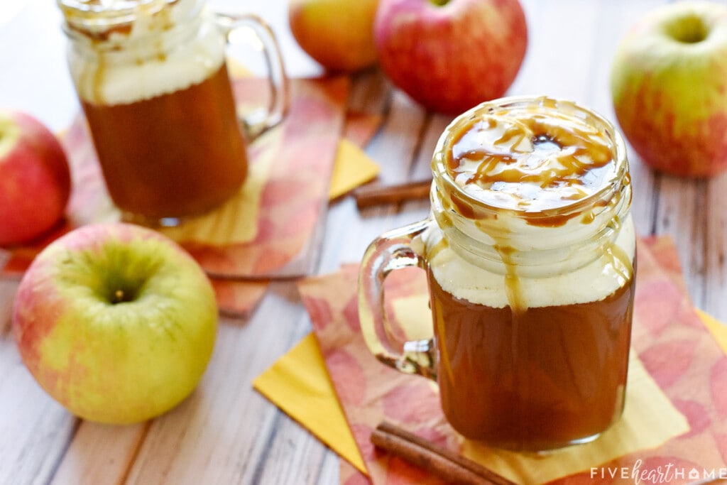 Caramel Apple Cider with cinnamon and apples on table.