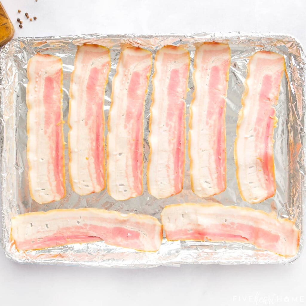 Raw bacon on baking sheet.