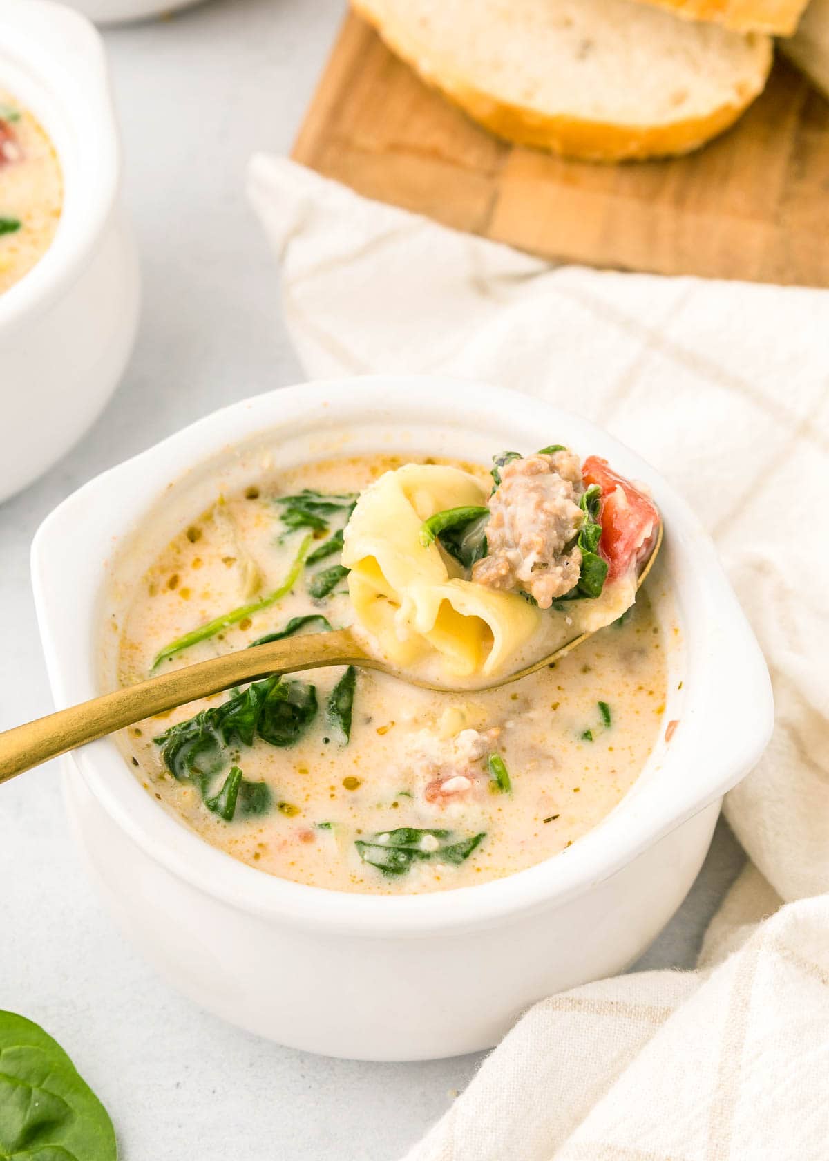 Sausage Tortellini Soup in spoon over bowl.