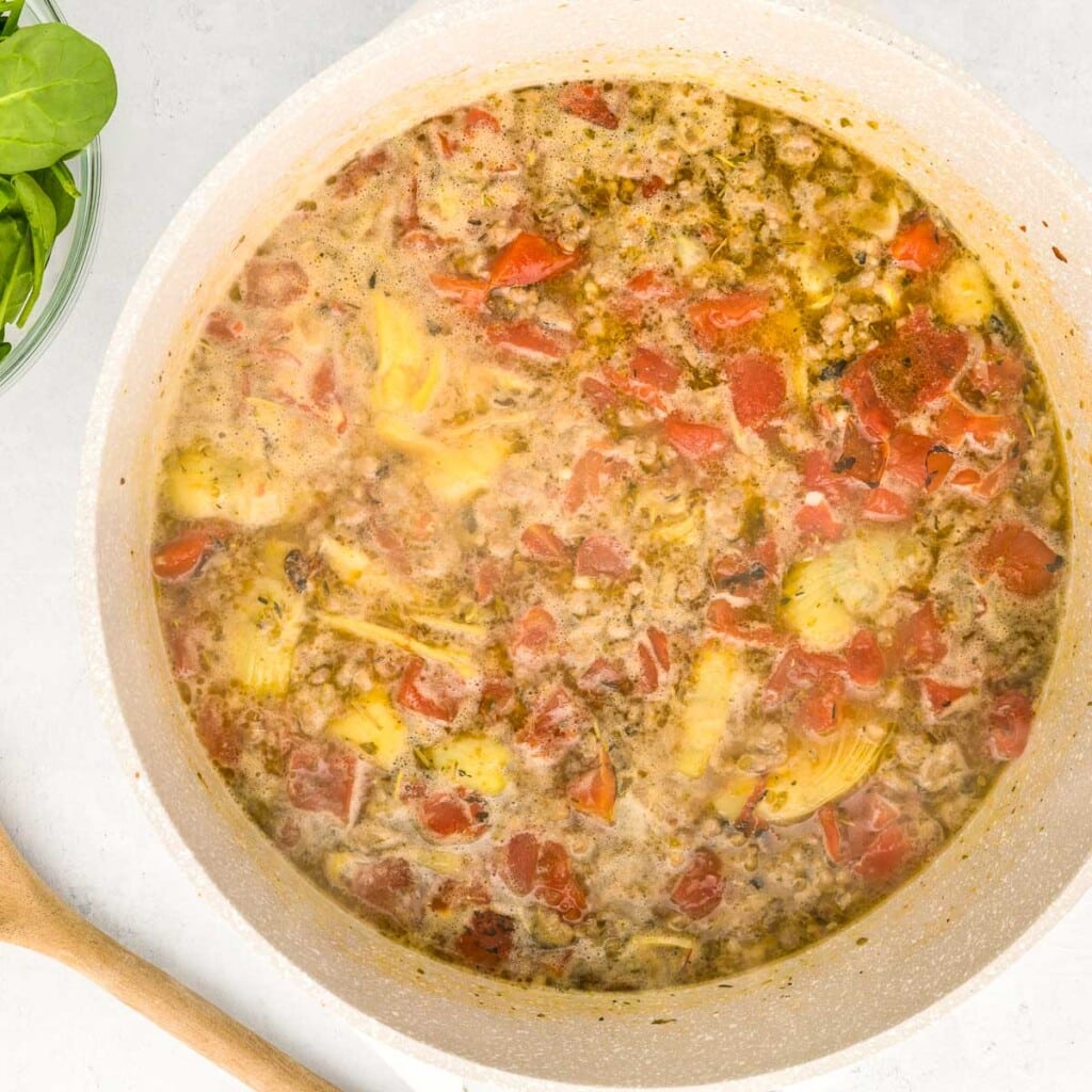 Italian Sausage Tortellini Soup boiling on stove.