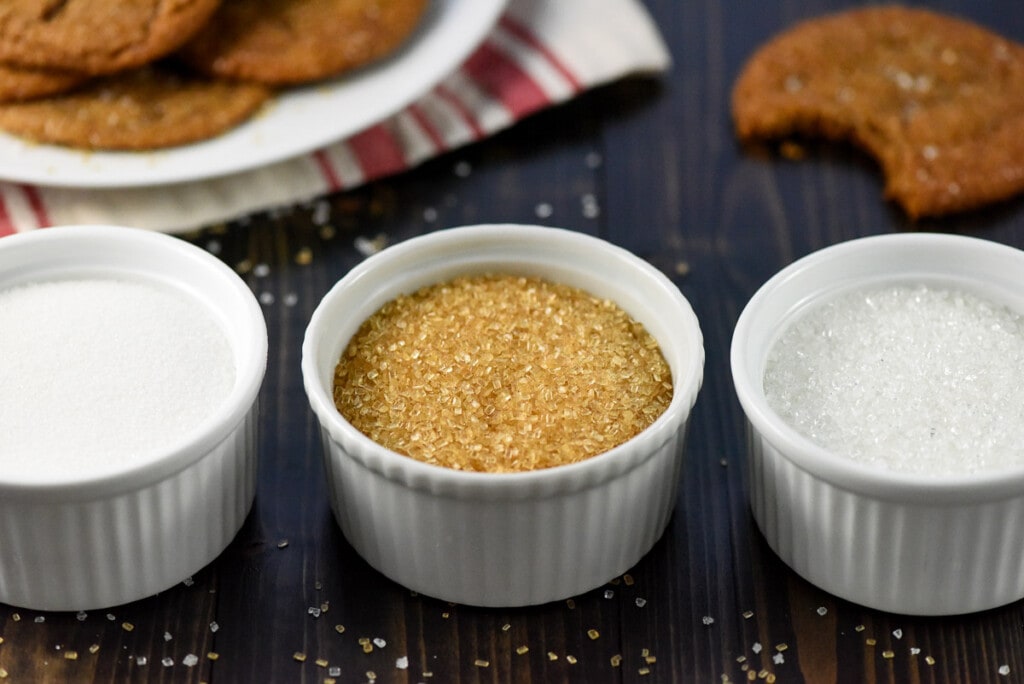 Granulated sugar, turbinado sugar, and sparkling sugar in three ramekins.