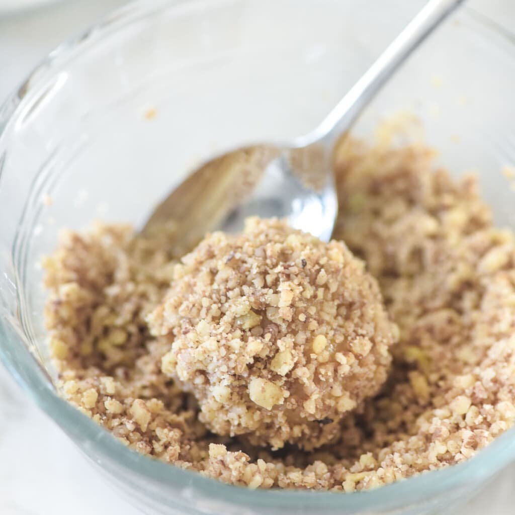 Coating thumbprint cookies recipe with nuts.