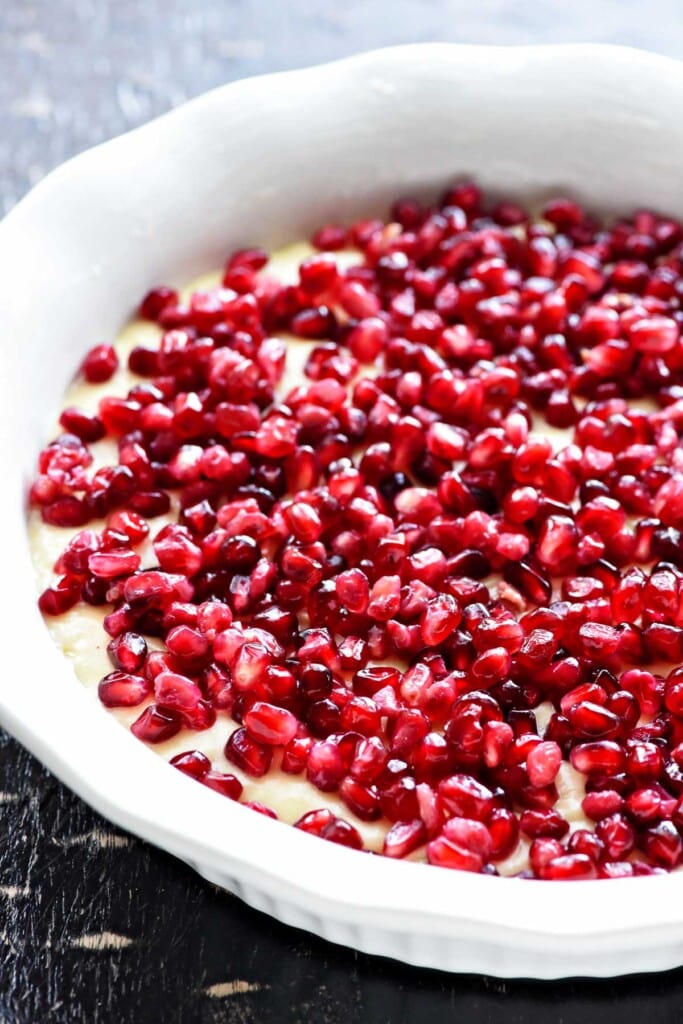 Pomegranate seeds sprinkled over cake batter.