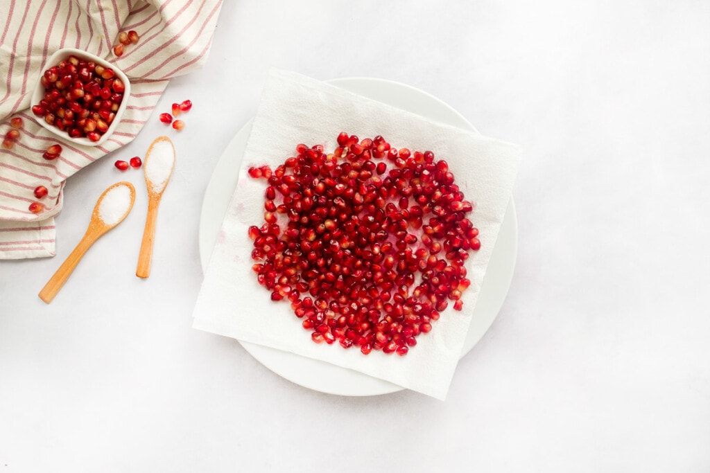 Pomegranate arils draining on paper towels.