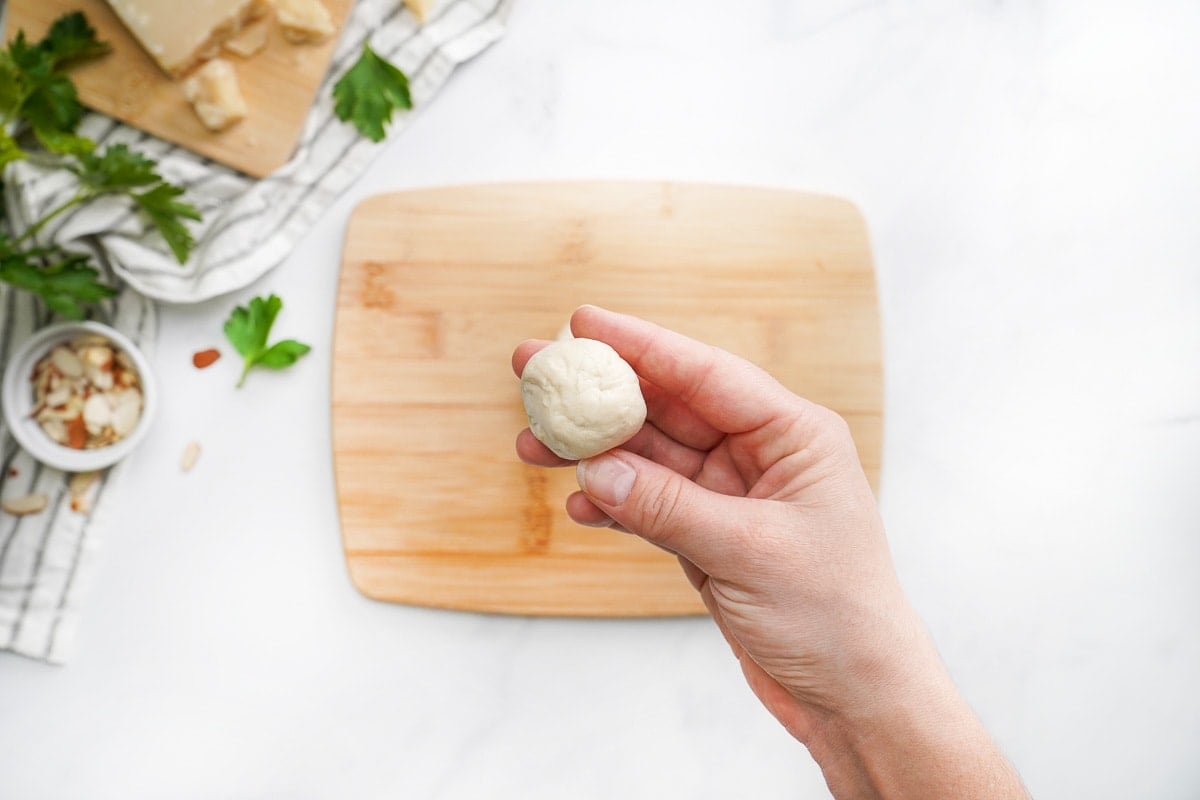 Rolling biscuit into ball for monkey bread recipe.