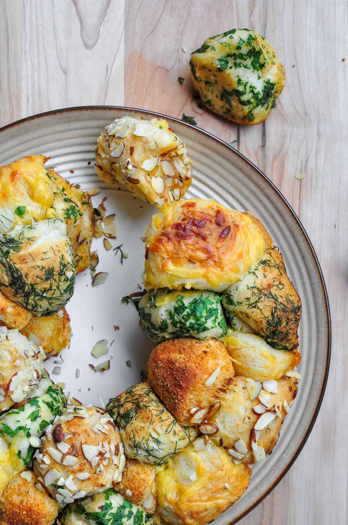 Monkey bread recipe showing herbs and cheese being pulled apart.