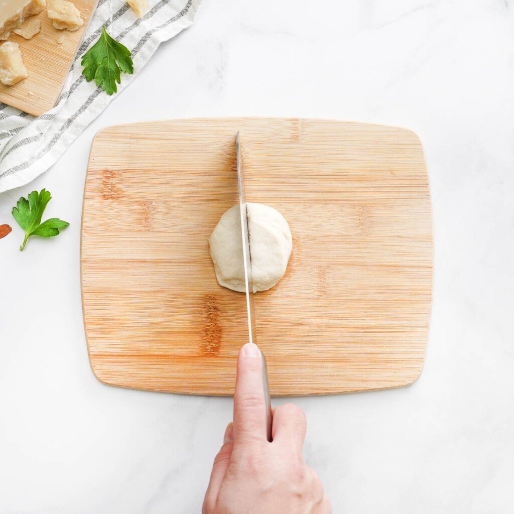 Cutting refrigerated biscuit in half.