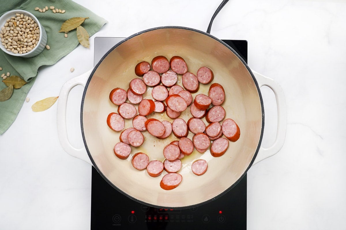 Sauteeing sausage in pot.