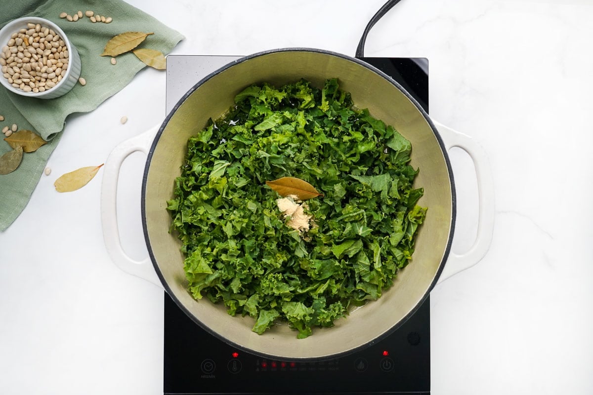 Adding greens and spices to Sausage Kale White Bean Soup.