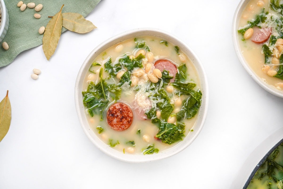 Kale and white bean soup with slices of sausage floating in broth.