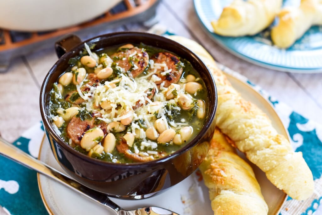 Sausage Kale White Bean Soup with breadsticks on side.