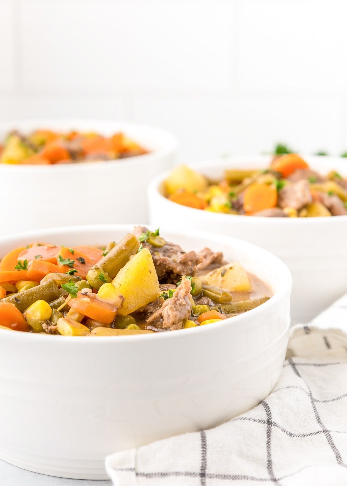 Three white bowls of beef stew in crock pot recipe.