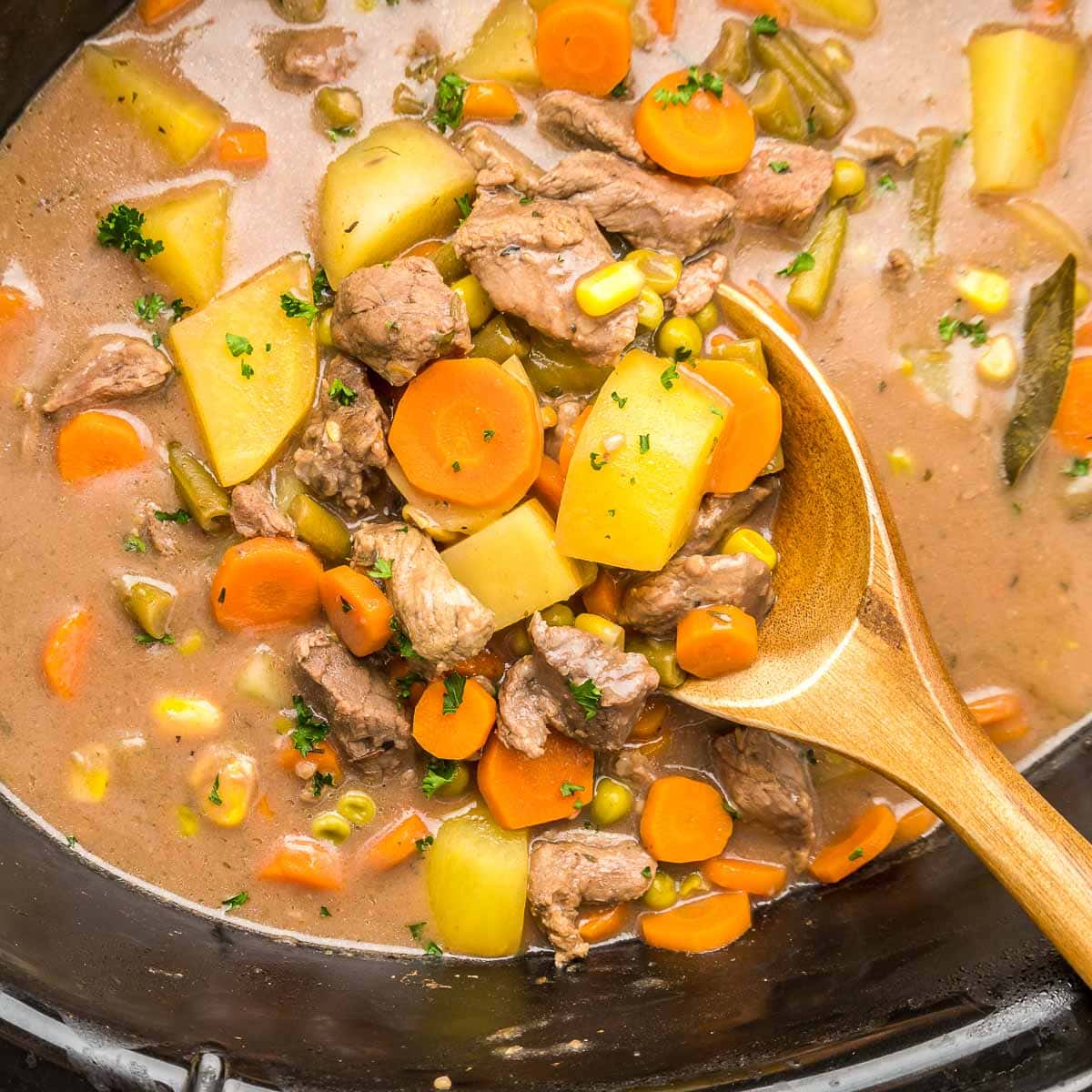 Crock Pot Beef Stew in slow cooker with wooden spoon.