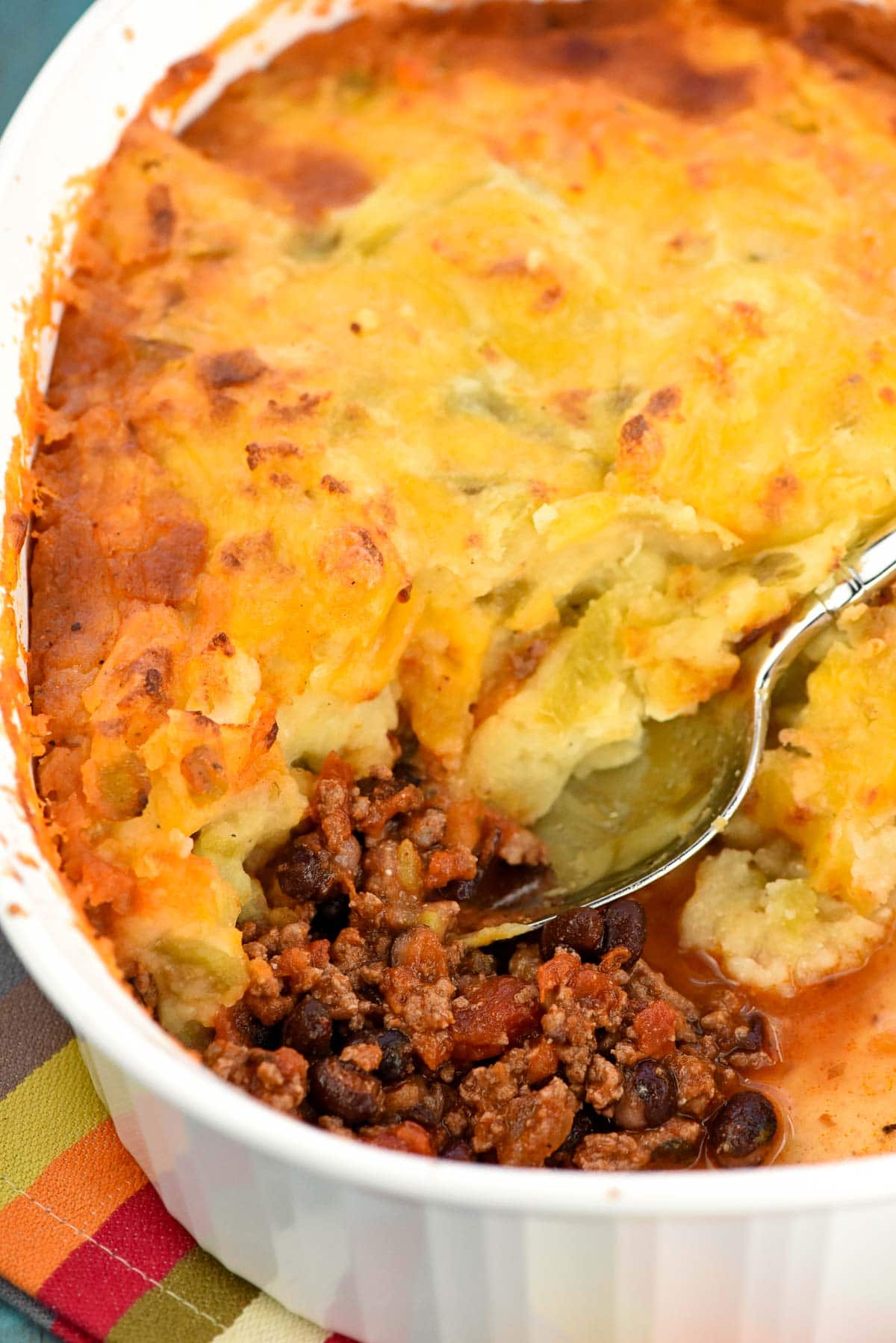 Taco Bake recipe in casserole dish with a serving missing.